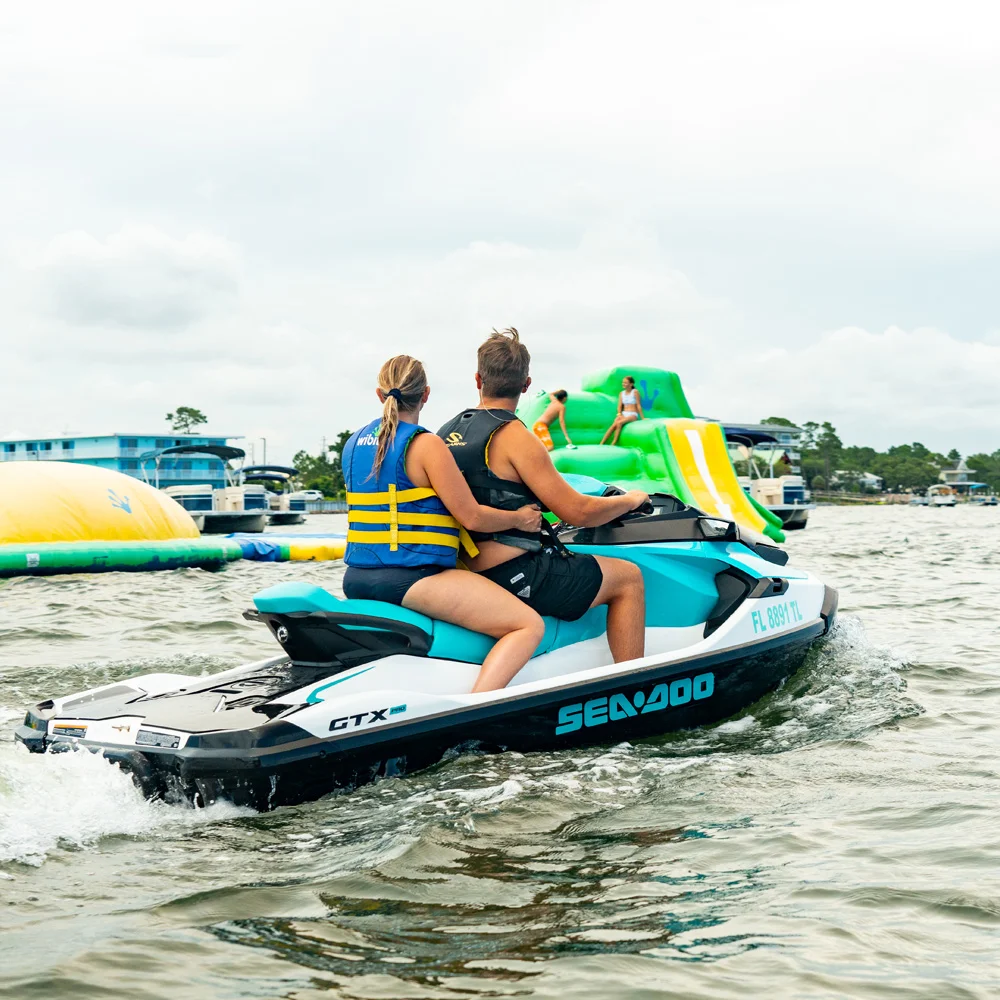A couple watches kids playing on the Wibit waterpark while driving their Waverunner nearby