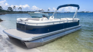 A blue Avalon Pontoon from Navarre Family Watersports beached on a sandy shoreline in Navarre, Florida